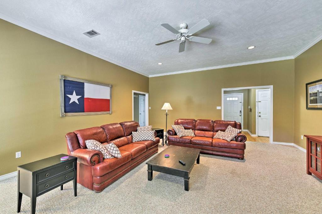 a living room with two leather couches and a ceiling fan at Cozy College Station Home with Patio and Fireplace in College Station