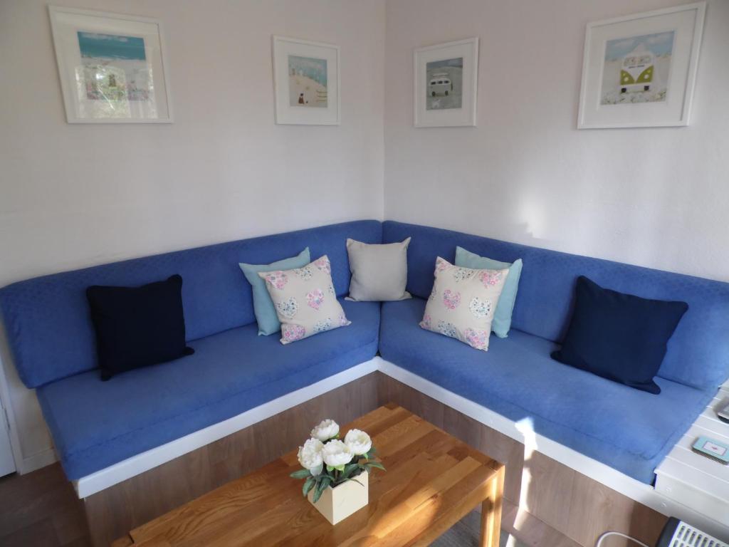 - un canapé bleu avec des oreillers et une table basse dans l'établissement Seaside Bungalow, à St Ives