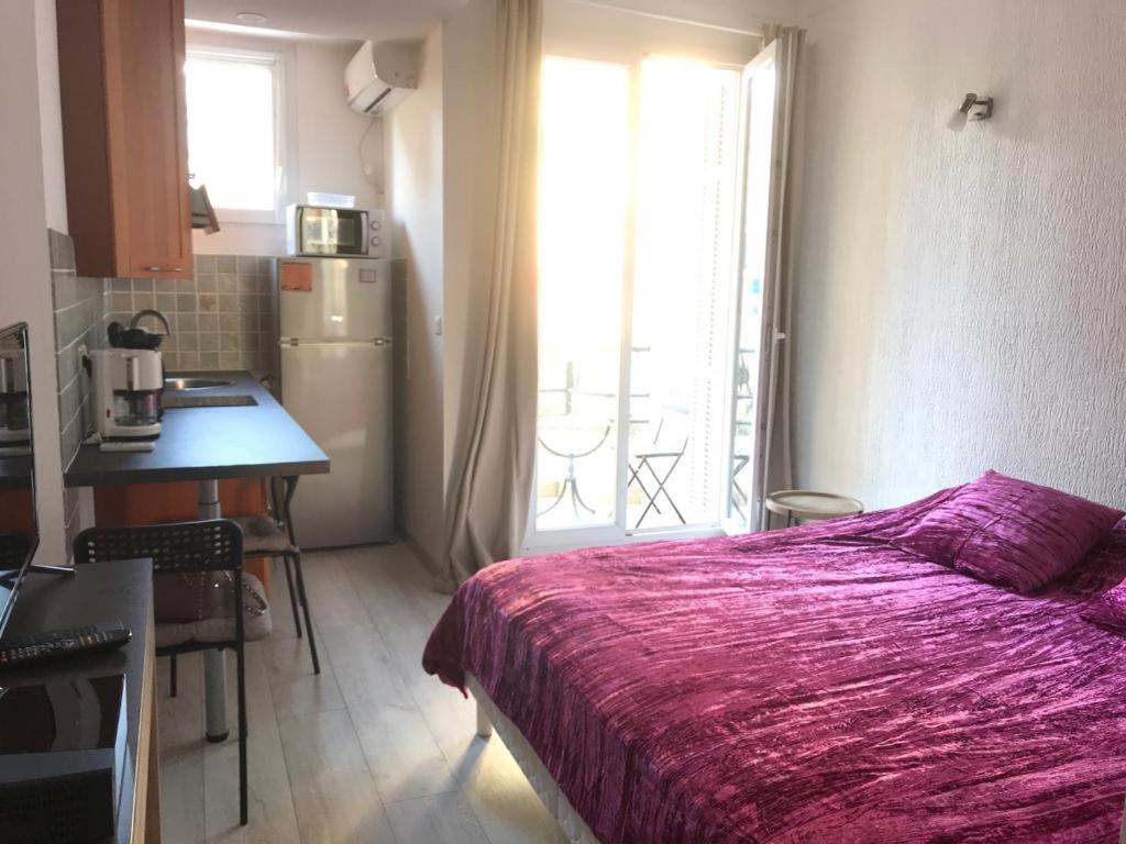 a bedroom with a bed and a table and a kitchen at chez Eva in Nice