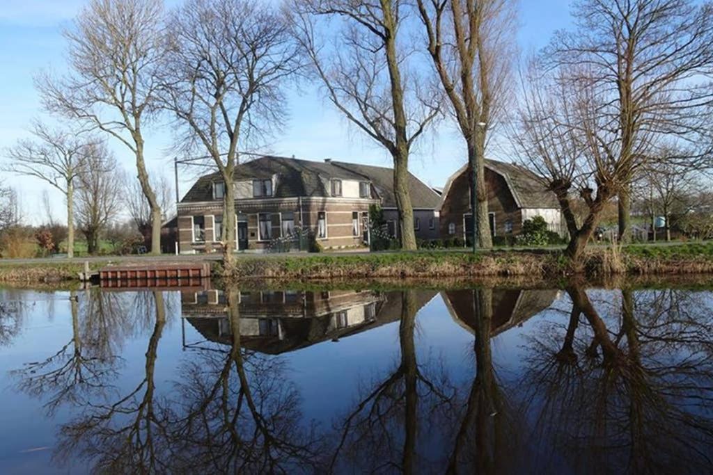 a large house with a reflection in the water at Mooi appartement in een prachtige fiets-wandelomgeving in Abcoude
