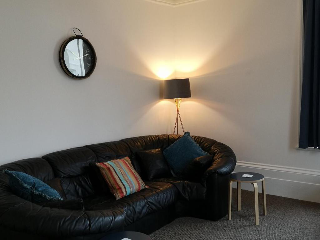 a black leather couch in a living room with a lamp at Coastal Escape Sandgate in Folkestone