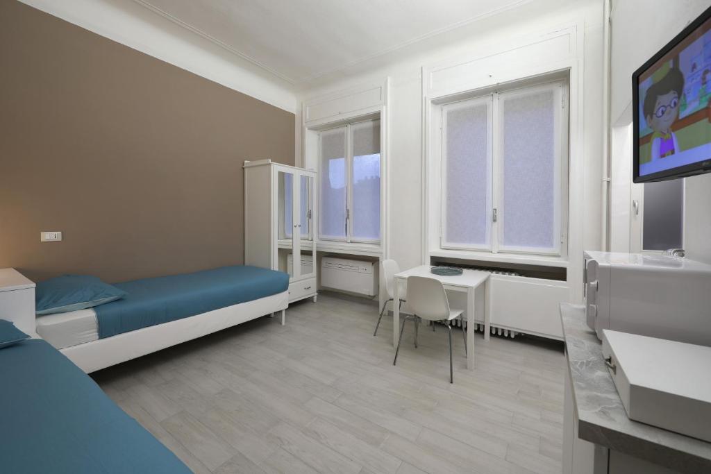 um quarto de hospital com uma cama, uma secretária e uma televisão em CASAJULIENNE em Milão