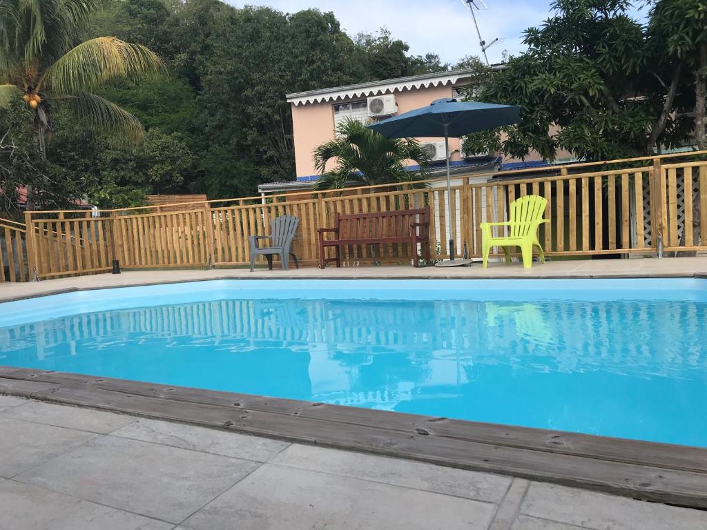 a swimming pool with two chairs and an umbrella at Vacances chez HélèneB Sublimes Vacances in Sainte-Anne