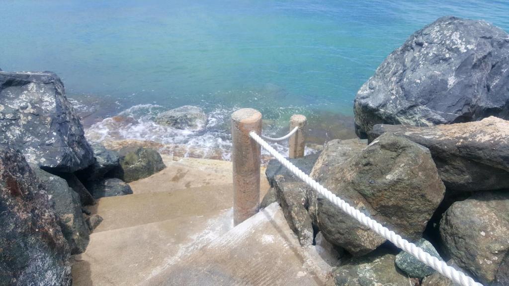 a set of stairs leading to the water with rocks at Cozy Beach Apartment in San Juan