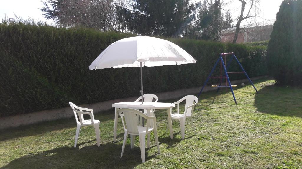 einen weißen Tisch mit 2 Stühlen und einem Sonnenschirm in der Unterkunft villa ROSE GARDEN in Craponne-sur-Arzon