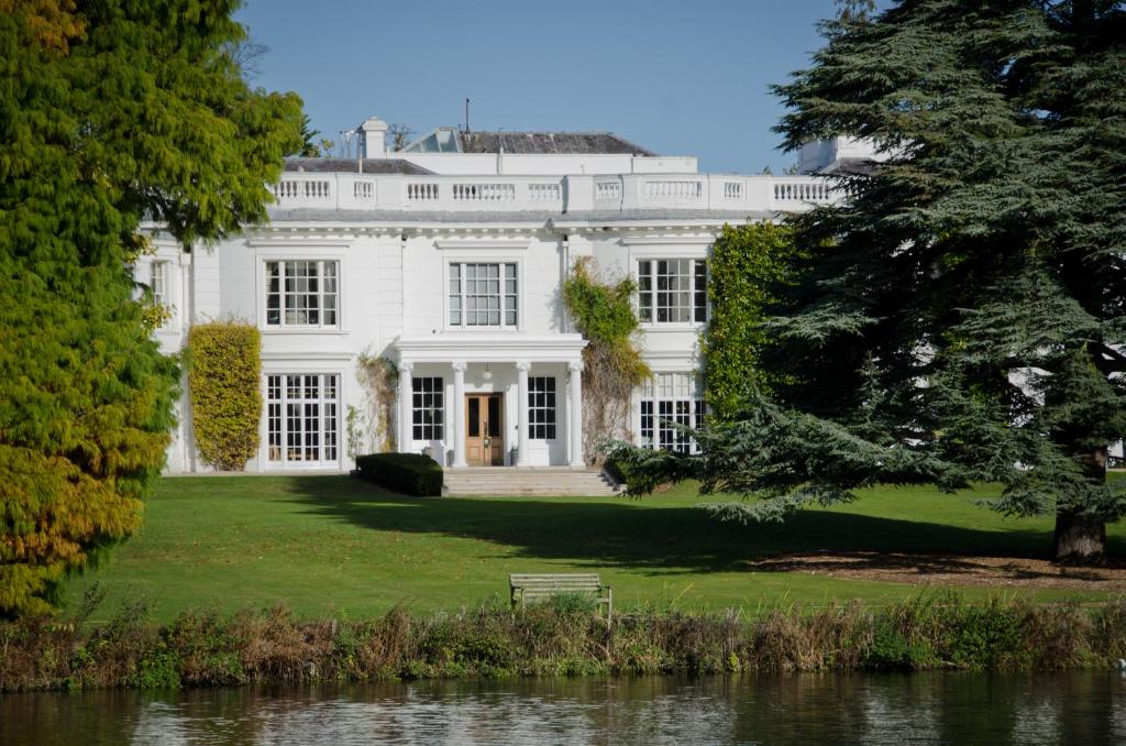 a white house with a bench in the yard at Greenlands Hotel in Henley on Thames