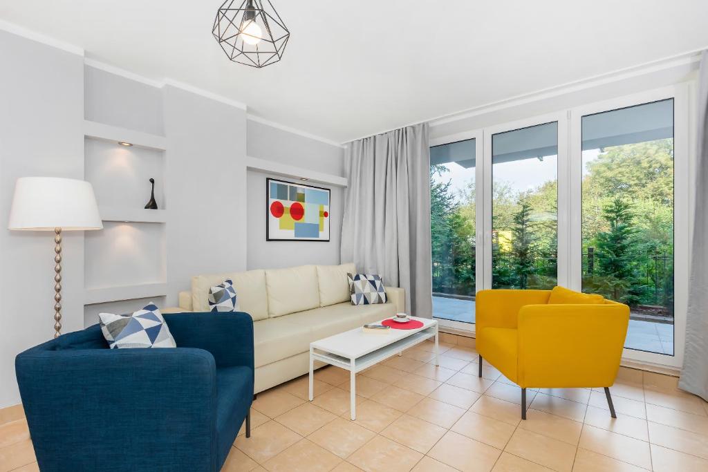 Contemporary sitting room with cream sofa, blue and yellow armchairs, white coffee table, floor lamp and patio windows.