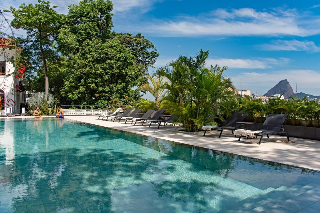 uma piscina com cadeiras e uma montanha ao fundo em Villa Paranaguá Hotel & Spa - Boutique Hotel no Rio de Janeiro