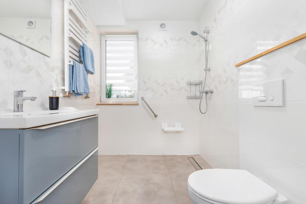 Bright accessible bathroom with wall-mounted shower, grab bars, sink and towel radiator.
