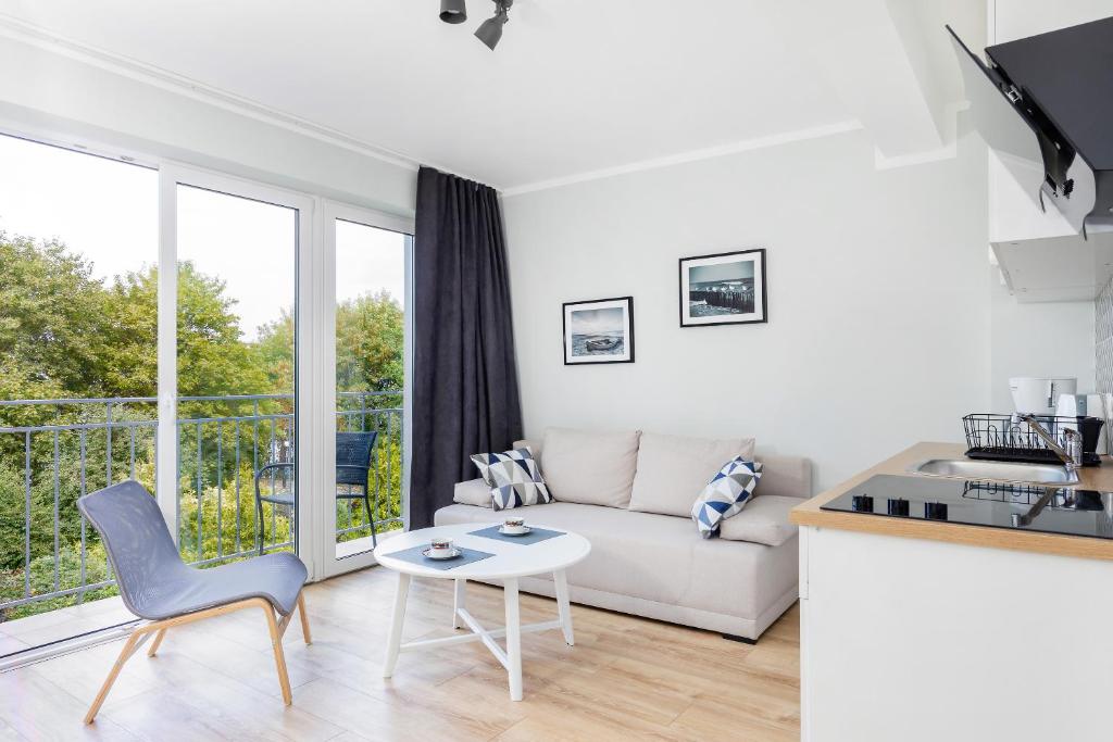 Bright living room with sofa, coffee table, accent chair, TV cabinet, and balcony doors.