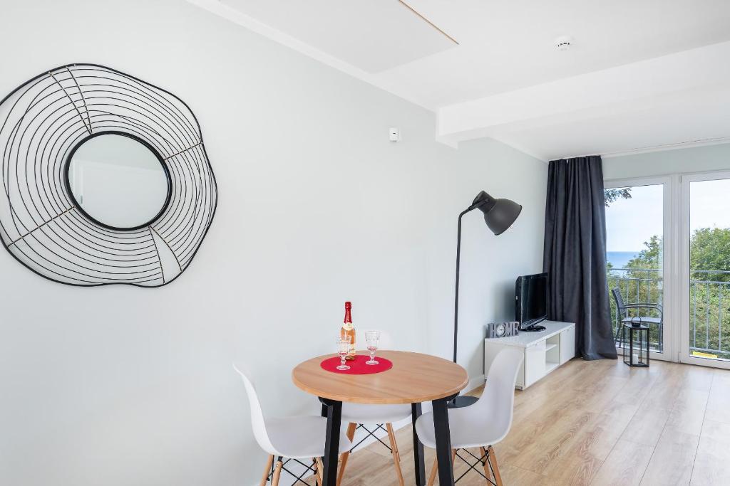 Small dining nook with bottle and glasses on table, floor lamp, lounge chair and balcony.