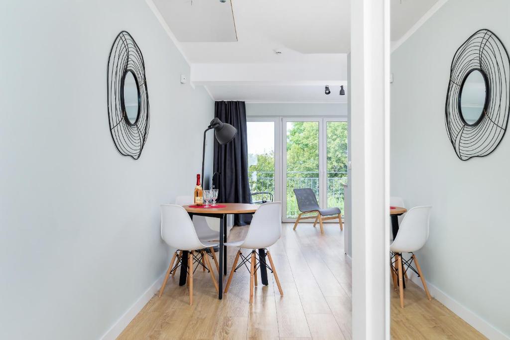 Narrow dining area with round table, two chairs, decorative mirror and balcony light.