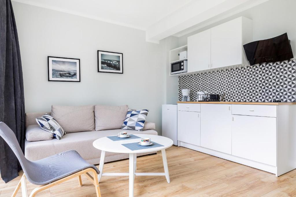 Compact living area with beige sofa, round coffee table, kitchenette and geometric backsplash, airy feel