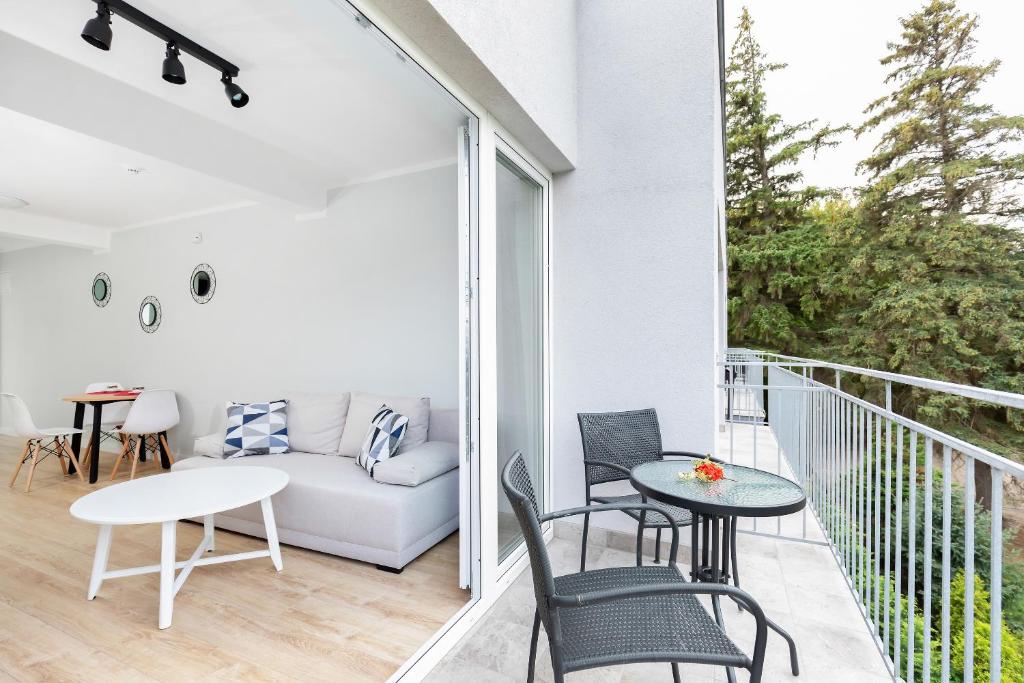 Open sliding doors connecting living room to balcony with seating, creating an airy coastal feel