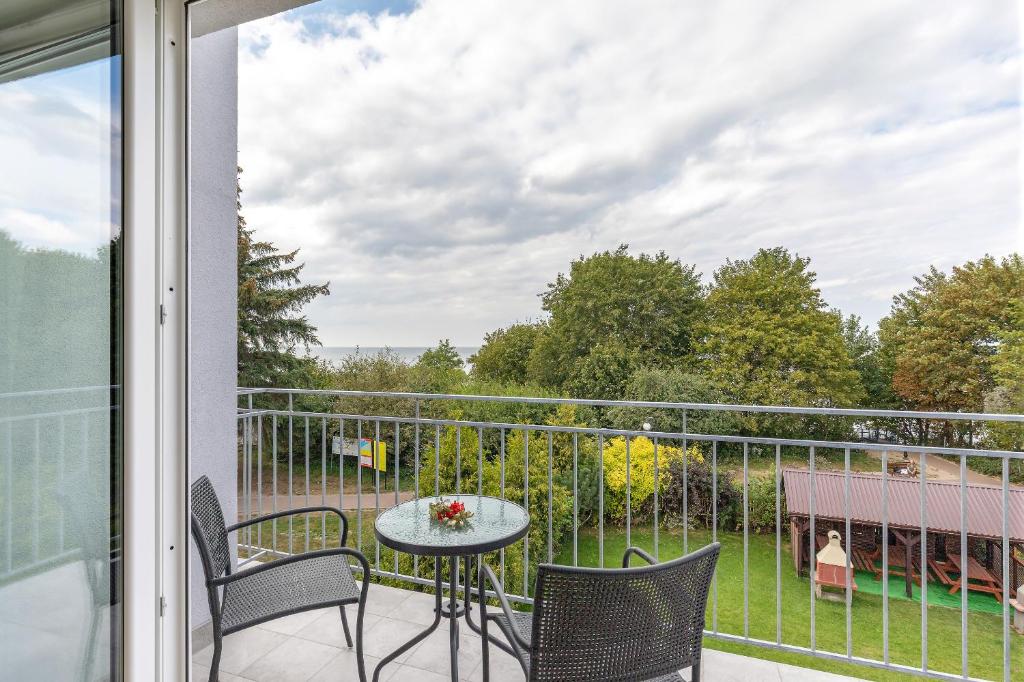Balcony with small glass table and two chairs overlooking trees and distant sea
