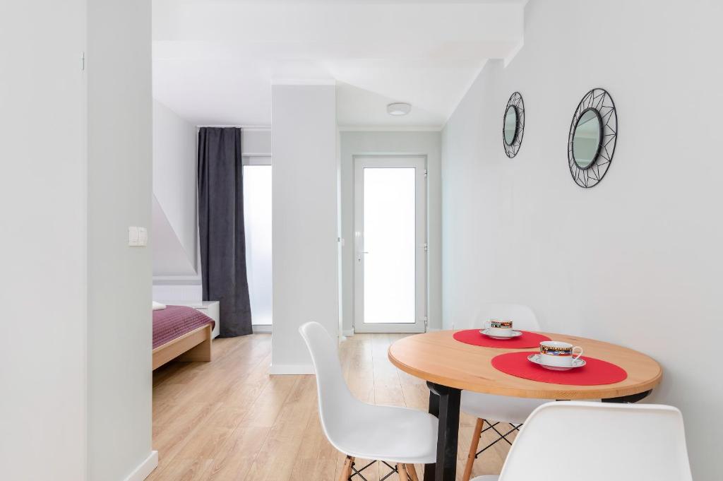 Dining nook with round wooden table set for two, modern chairs, doorway to bedroom
