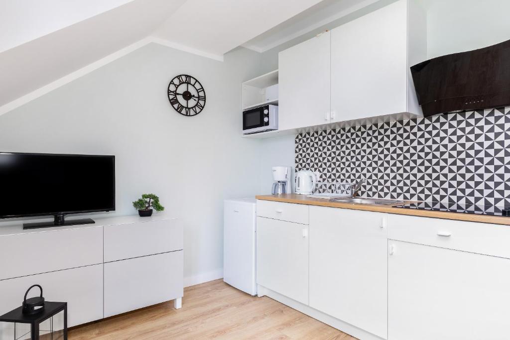 Small kitchen area with patterned tile backsplash, sink, kettle, coffee maker and TV nearby