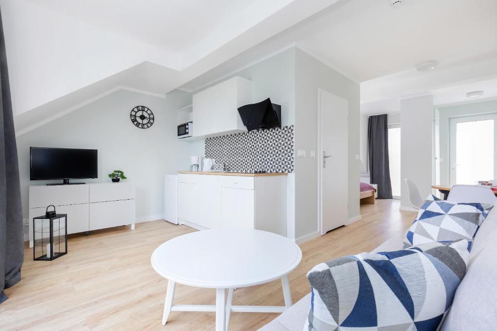Open-plan living area with sofa, round table, kitchenette and doorway leading to bedroom
