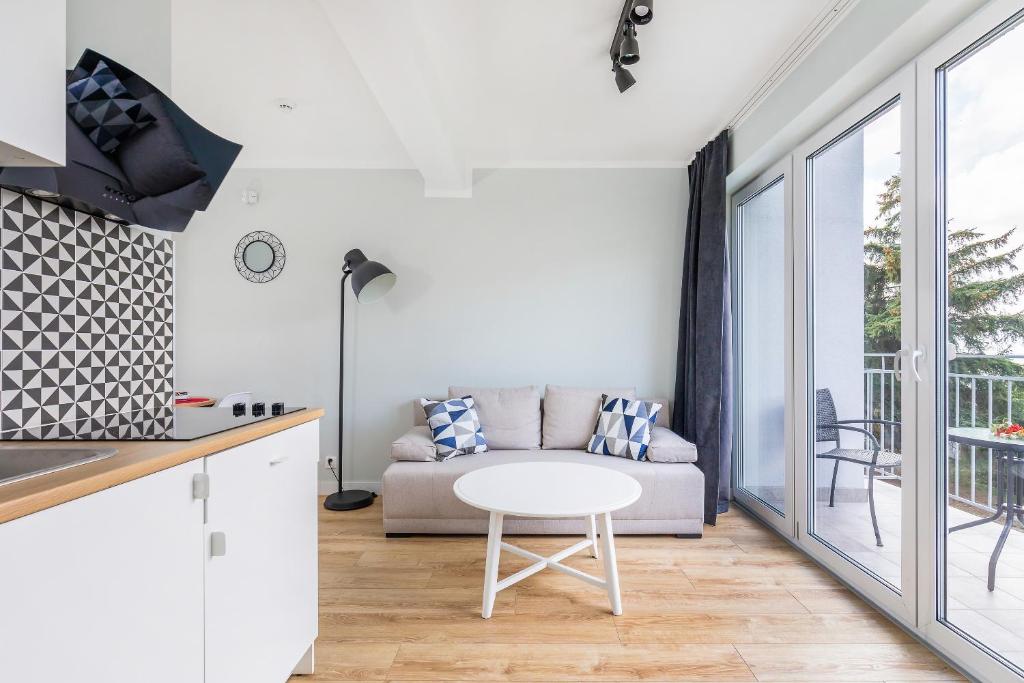 Bright living room with beige sofa, geometric pillows, round white coffee table, balcony doors