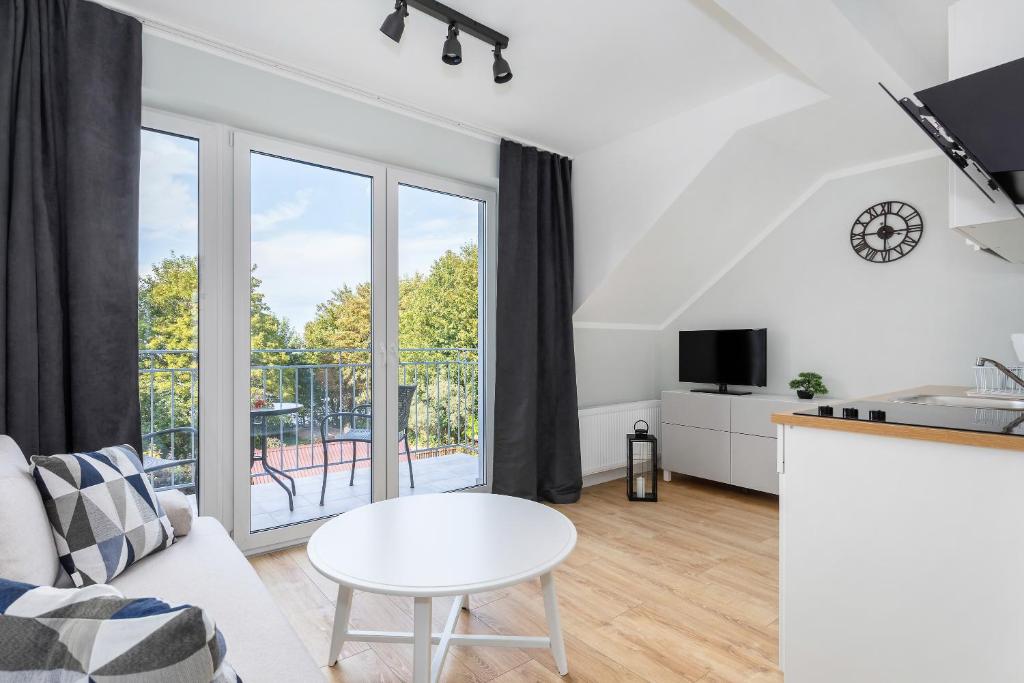 Living area with large glass doors opening to balcony, sofa, white coffee table and TV