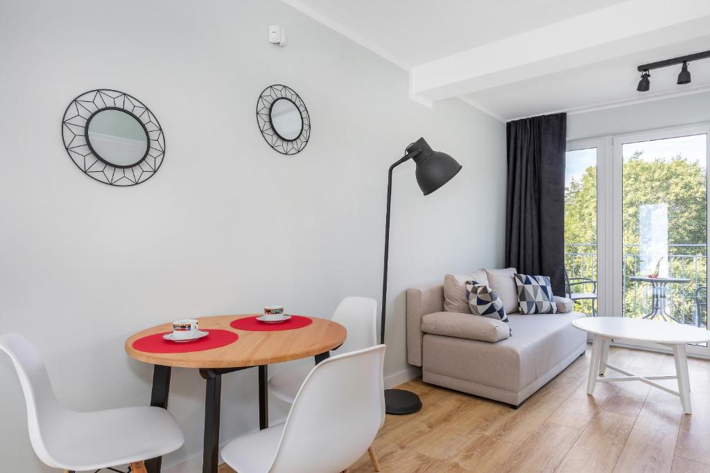 Dining nook with round wooden table, four white chairs, sofa and decorative wall mirrors