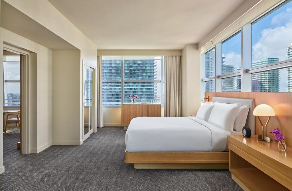 マイアミにあるHotel AKA Brickellのベッドと大きな窓が備わるホテルルームです。