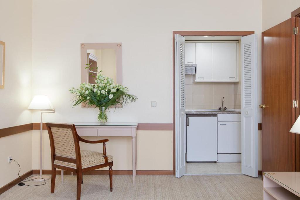 a living room with a chair and a kitchen at Espahotel Plaza Basílica in Madrid