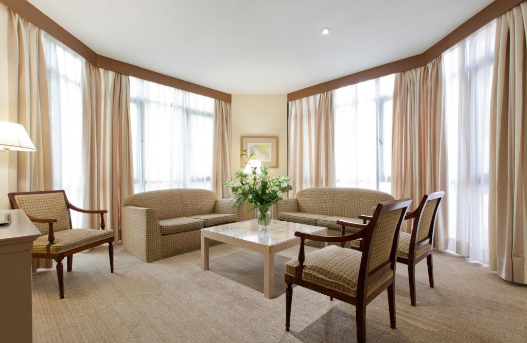a living room with a couch and a table and chairs at Espahotel Plaza Basílica in Madrid