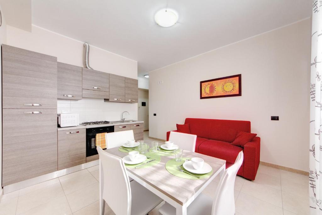 una cucina e un soggiorno con tavolo e divano rosso di Olimpo Apartments St John in Lateran a Roma