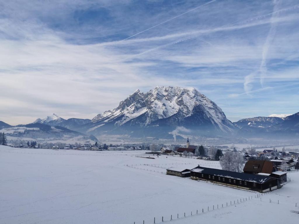 a snow covered mountain in front of a city with a train at Ferienwohnung - Apartment Pichlarn Irdning in Aigen im Ennstal