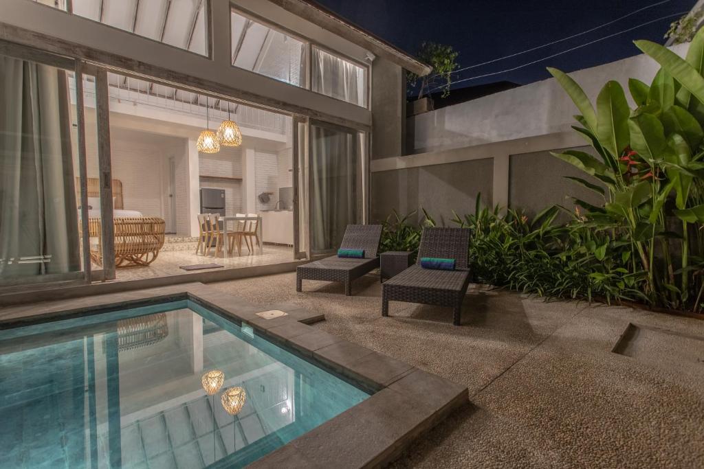 a house with a swimming pool and two chairs at White Studio, villa with private pool Canggu in Canggu