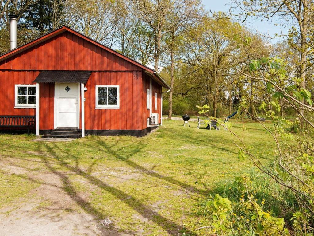 une grange rouge avec une porte blanche dans un champ dans l'établissement 5 person holiday home in Skærbæk, à Skærbæk