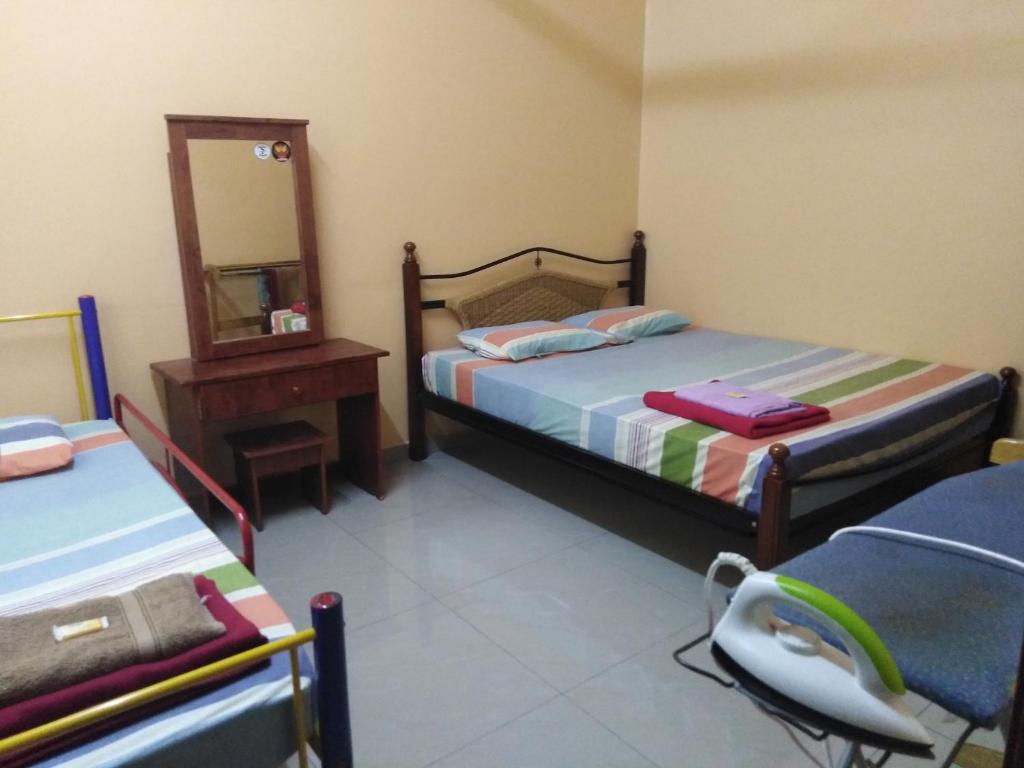 a bedroom with two beds and a mirror and a chair at Homestay Teratak Umi Klang in Klang