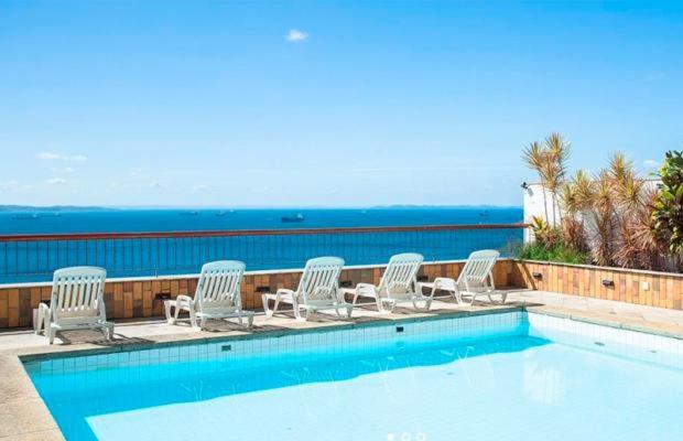 un grupo de sillas sentadas alrededor de una piscina en VICTÓRIA MARINA FLAT - vista avenida, en Salvador