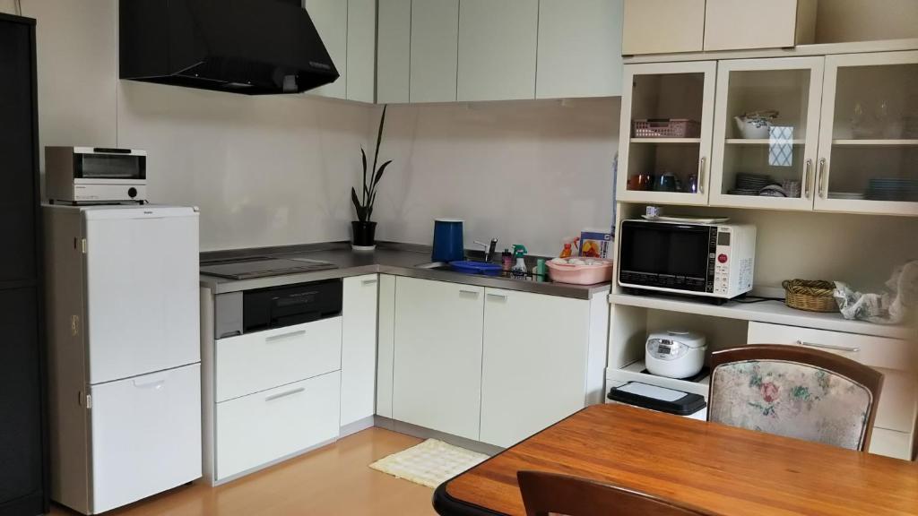 a kitchen with white cabinets and a wooden table at 町中ステイ 宗ハウス in Nachikatsuura