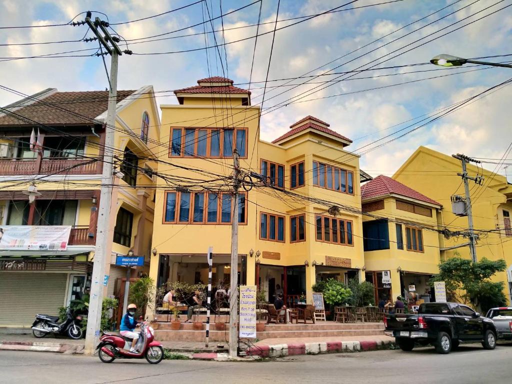 una casa amarilla con una moto aparcada delante de ella en Ban Mae Boonthong en Lampang