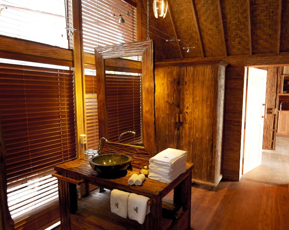 a bathroom with a sink and a mirror on a table at Puri Dajuma Beach Eco-Resort & Spa in Pulukan