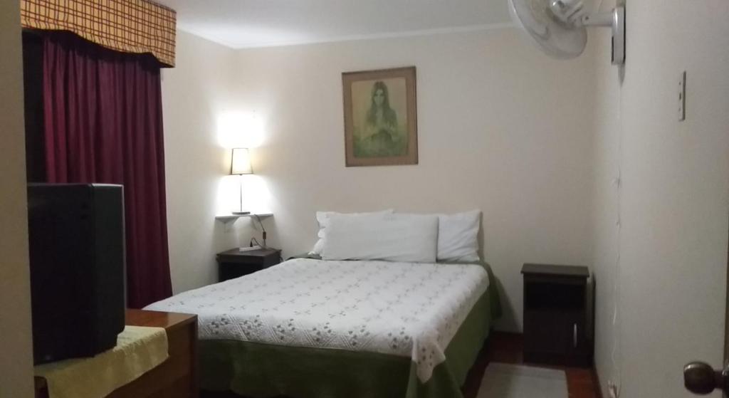 a small bedroom with a bed and a tv at Guesthouse Playa Chinchorro in Arica