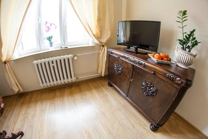 a room with a television on a dresser with a bowl of fruit at Apartament Ołowianka- Danzig in Gdańsk