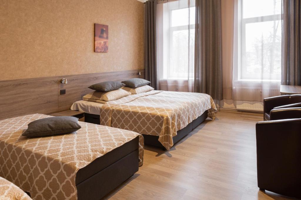 a hotel room with two beds and a chair at Sweet Apartments in Šiauliai