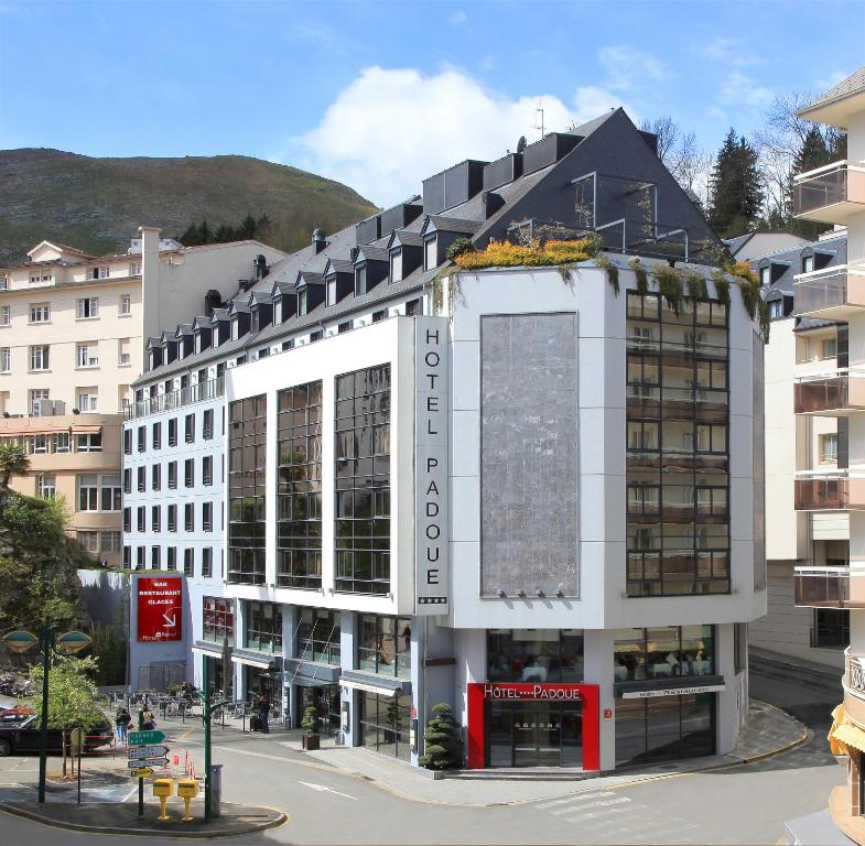 un grand bâtiment blanc au cœur d'une ville dans l'établissement Hôtel Padoue, à Lourdes