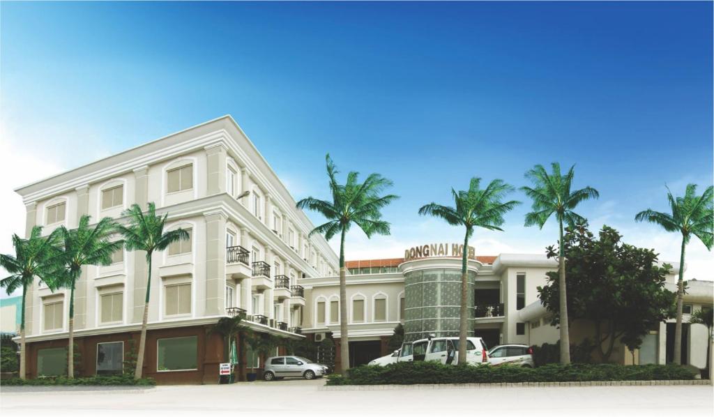 a white building with palm trees in front of it at Khách sạn Đồng Nai in Bien Hoa