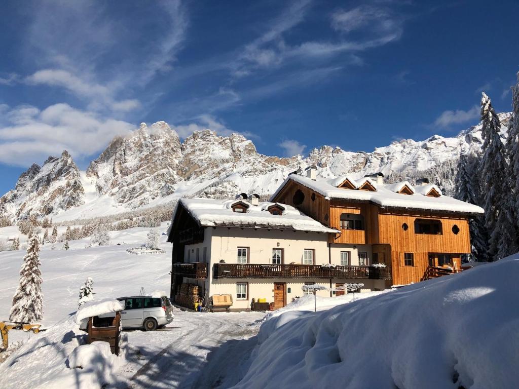 un edificio nella neve di fronte a una montagna di Ciasa Coletin a Alvera