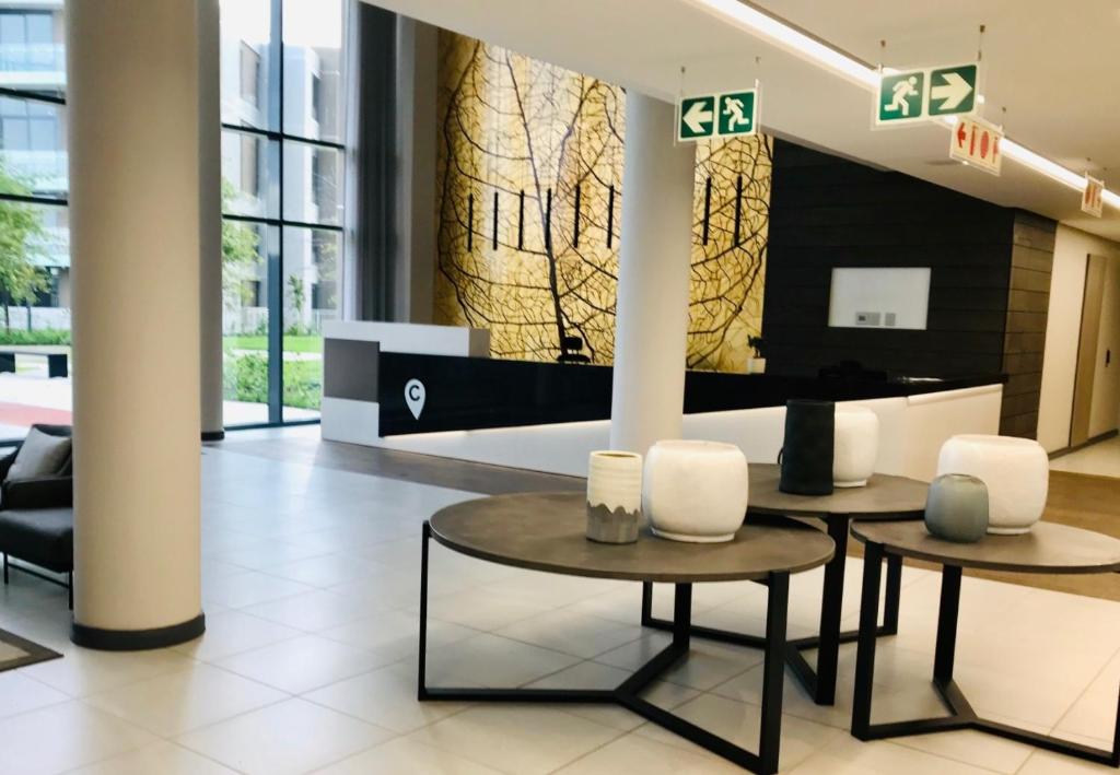 a lobby with two tables and chairs in a building at MENLYN MAINE - One Bedroom Penthouse - NO LOAD SHEDDING!! in Pretoria