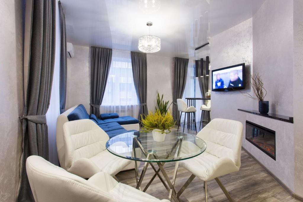 a living room with a glass table and white chairs at New luxury Apartment in the Center on Konstitution Square in Kharkiv