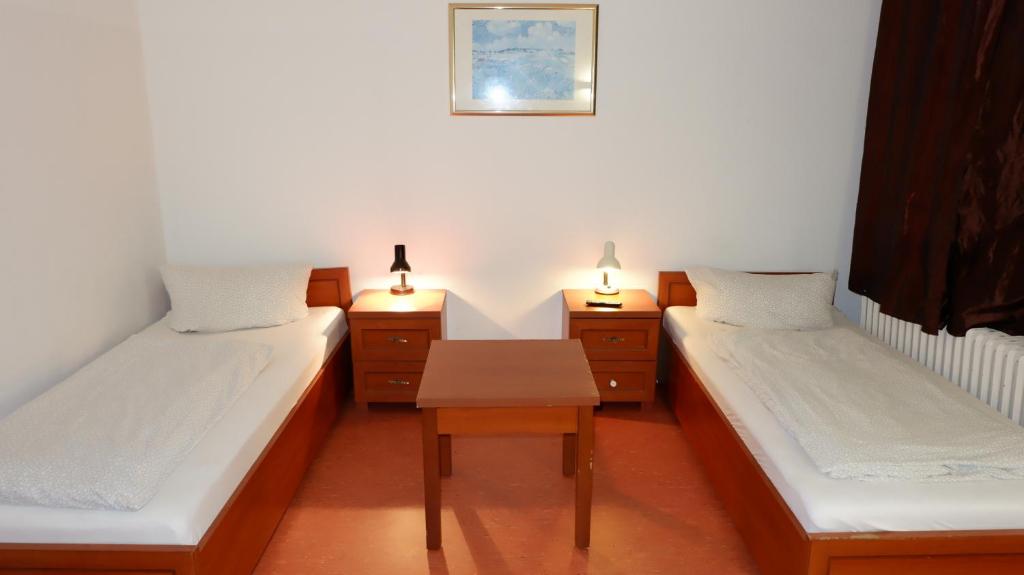 two beds in a room with a table and two lamps at Hostel am Kurtti in Berlin