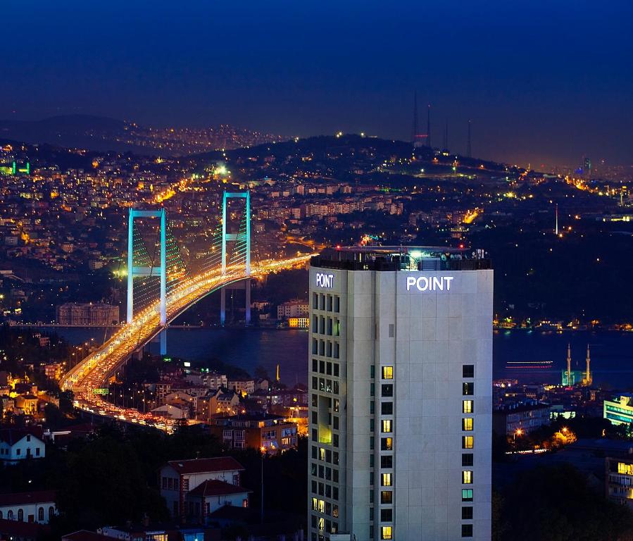 a point building with a bridge in the background at night at Point Hotel Barbaros in Istanbul