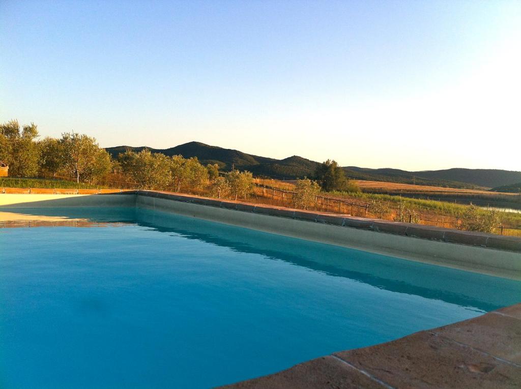 una piscina di acqua blu con montagne sullo sfondo di Villa Belvedere a Marsiliana