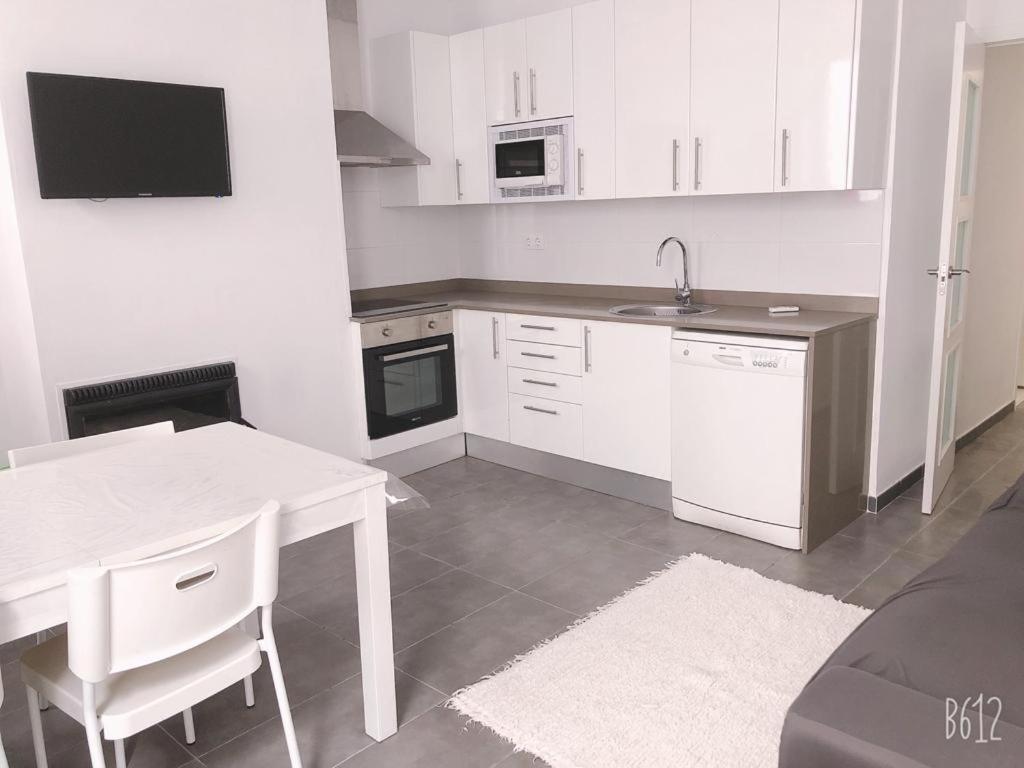 a white kitchen with a table and a sink at Fantástico Apartamento en el centro de Blanes y a 150mts de la Playa in Blanes