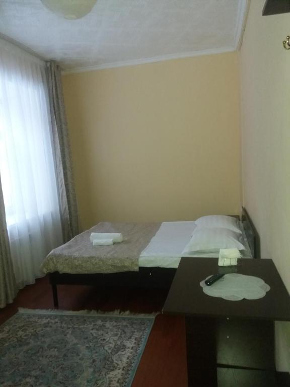 Habitación pequeña con cama y mesa en Гостиница "SEMEY-CITY" en Semey